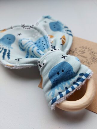 A bunny teether for babies in a sea creatures print: jersey and bamboo towelling fabric in the shape of bunny ears, on a wooden ring
