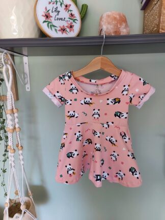 A short childrens dress in a pink design with pandas.